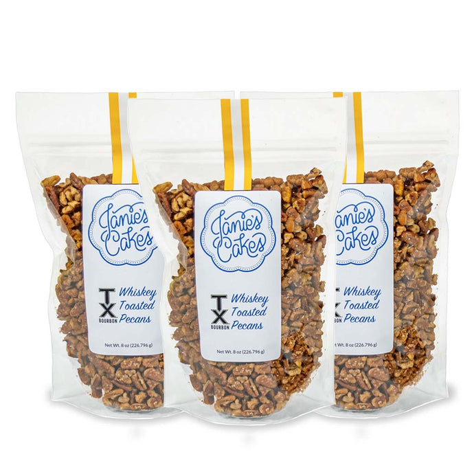 Three packages of Janie's Cakes whiskey toasted pecans in clear packaging.