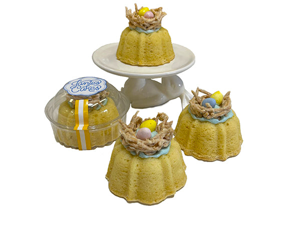These are eggsquisite Easter Nest Petite Janes!    Vanilla pound cake  filled with an light blue vanilla buttercream  topped with a white chocolate coated chow mein noodle Easter nest  that is garnished with two pastel milk chocolate candy eggs.